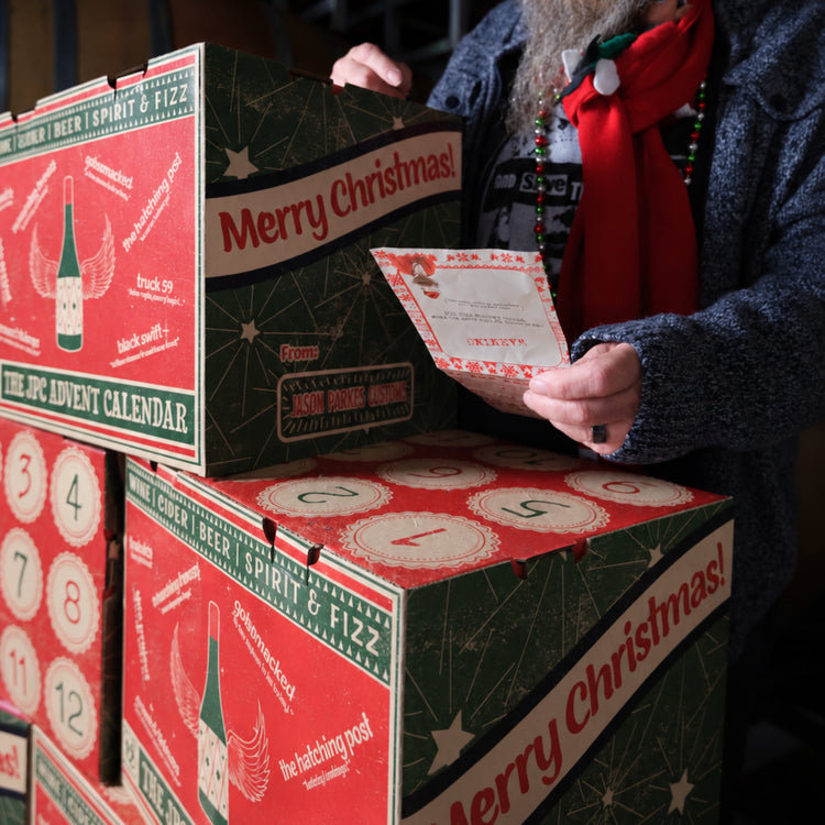 The Hatch wine advent calendar displayed with wine bottles in the winery barrel cellar